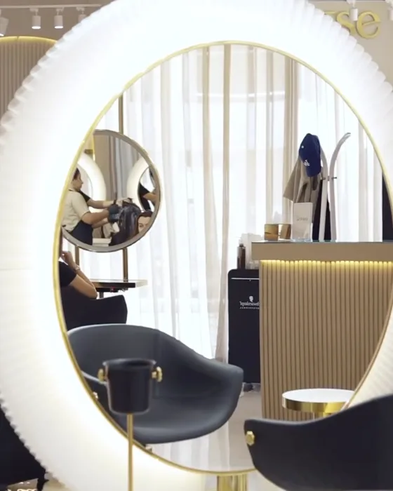 Grand miroir circulaire lumineux et fauteuil noir dans la salle de coiffure