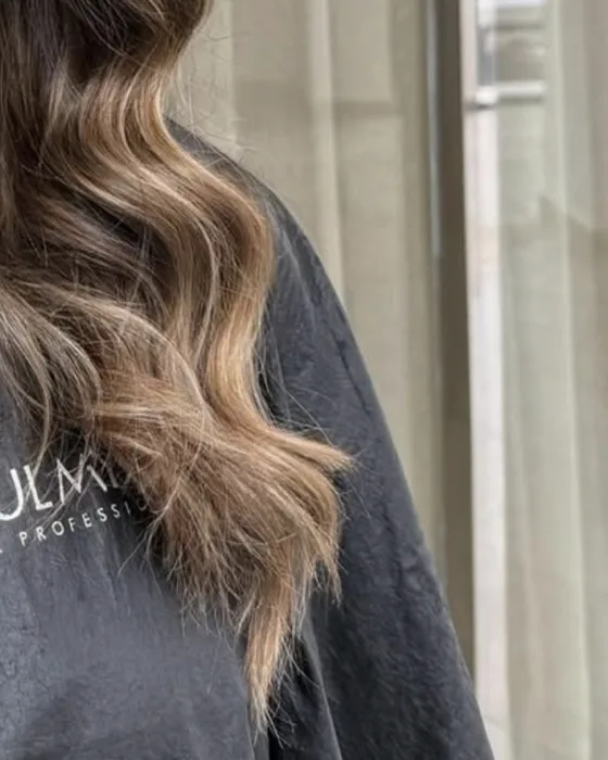 Longueurs ondulées après un balayage naturel, reflets clairs sur les pointes
