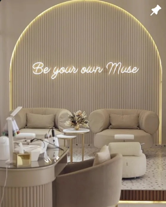 Néon Be your own Muse au-dessus des fauteuils crème de l'espace d'attente