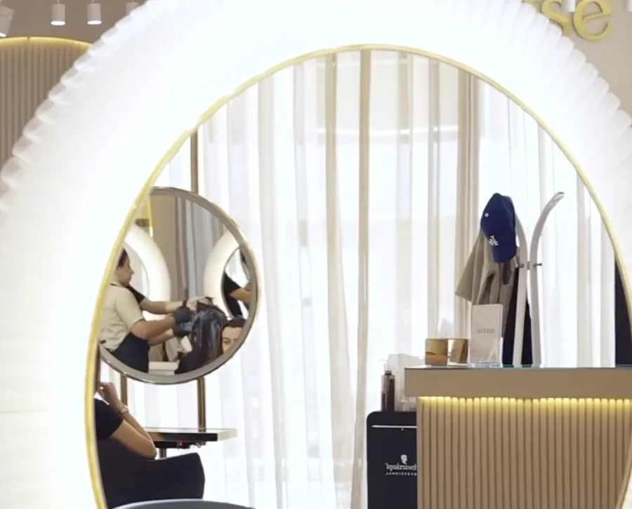 Miroir circulaire lumineux et fauteuil noir dans la salle de coiffure du salon